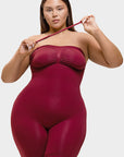 Woman wearing a maroon bodysuit against a white background