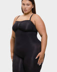 Woman wearing a black shapewear bodysuit on a white background