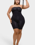 Woman wearing a black strapless bodysuit against a white background