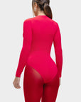 Person wearing a bright pink bodysuit with sheer panels on a white background