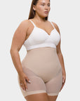 Woman wearing a white bra and beige shapewear on a plain background