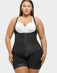 Woman wearing a black shapewear garment over a white bra on a plain background
