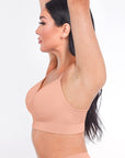 Woman wearing a peach-colored sports bra and leggings on a white background