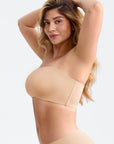 Woman wearing a beige shapewear garment against a plain background