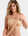 Woman wearing a beige strapless top against a plain background