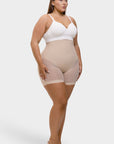 Woman wearing beige shapewear and a white top on a white background