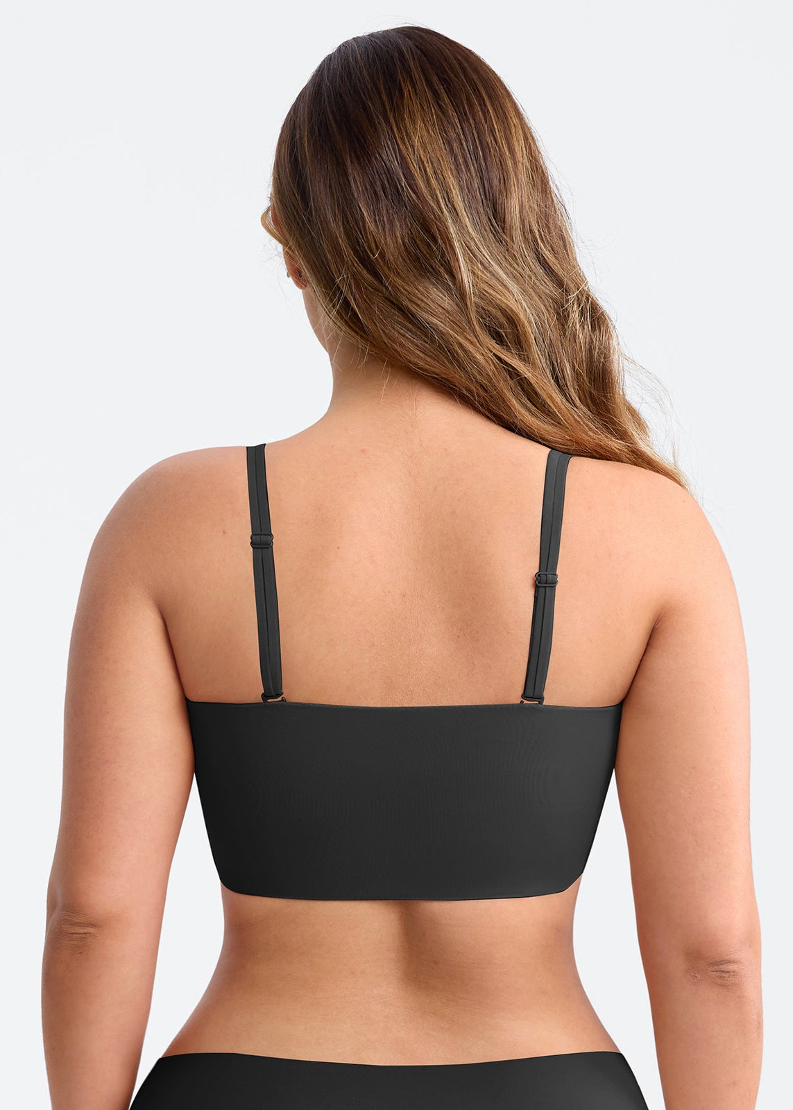 Black sports bra worn by a person on a light gray background
