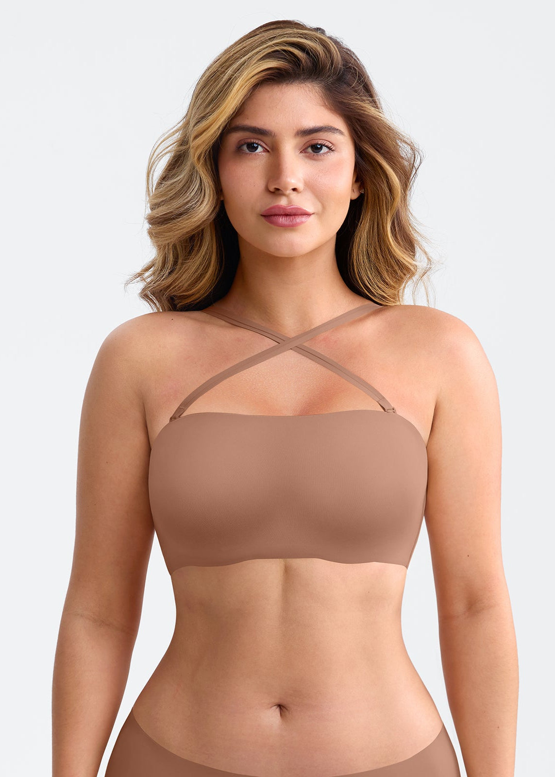 Woman wearing a beige strapless top against a plain background