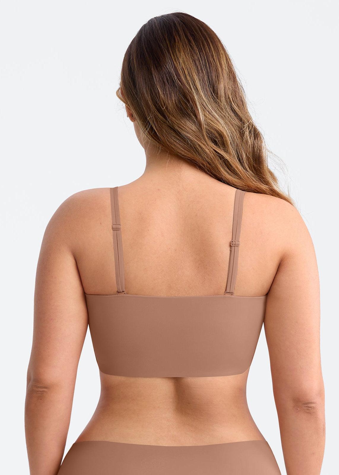 Woman wearing a brown bralette on a light gray background