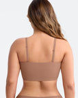 Woman wearing a brown bralette on a light gray background
