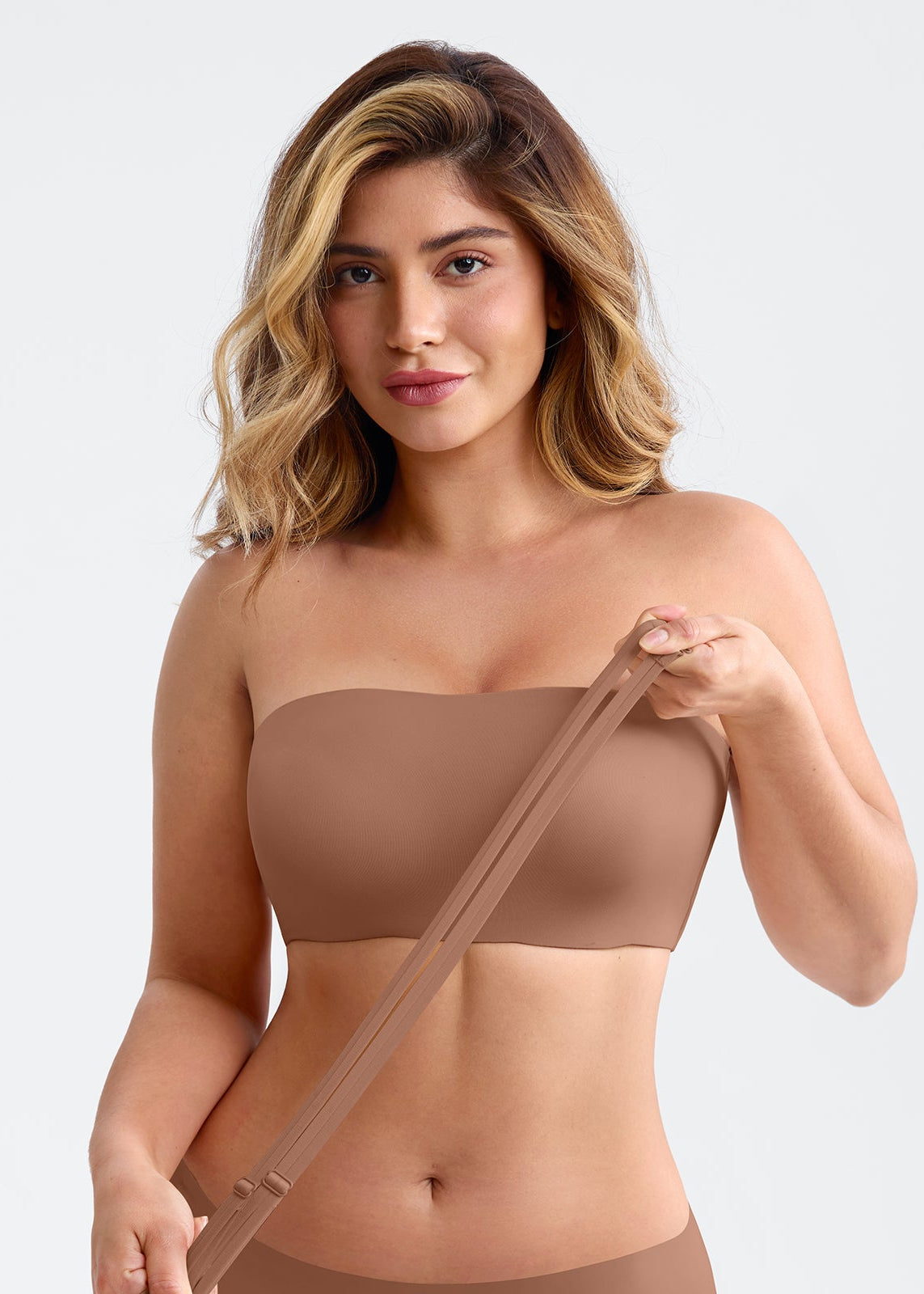 Woman wearing a brown strapless top against a plain background