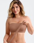 Woman wearing a brown strapless top against a plain background