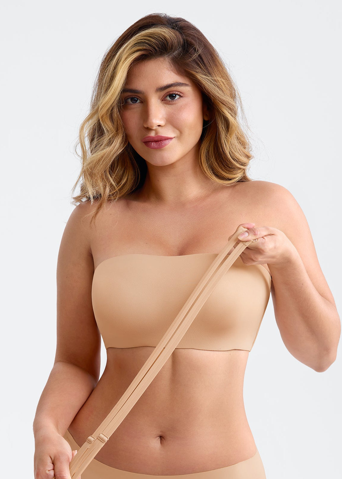 Woman wearing a beige strapless top against a plain background