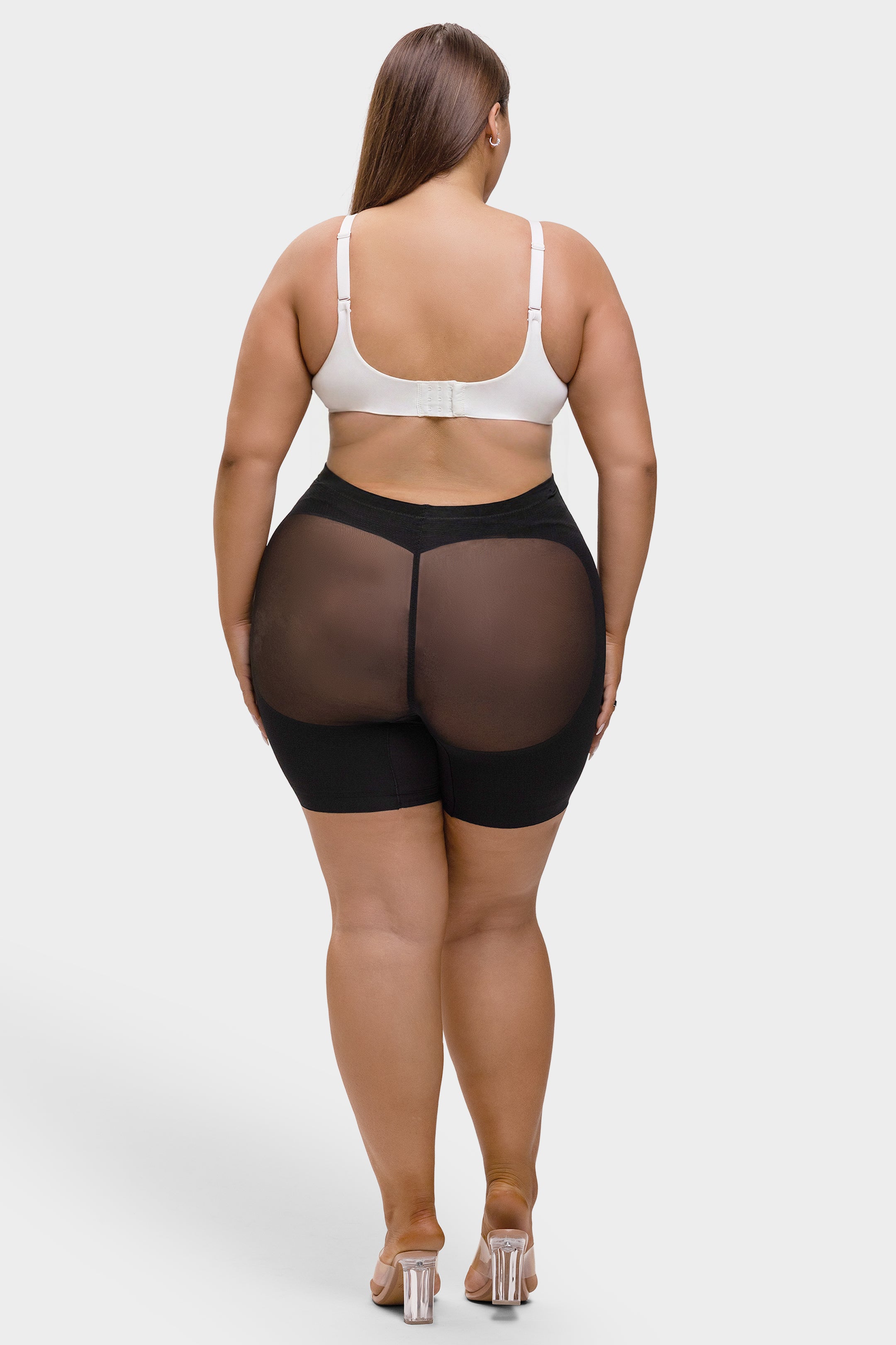 women wearing a white bra and black sheer shorts on a white background