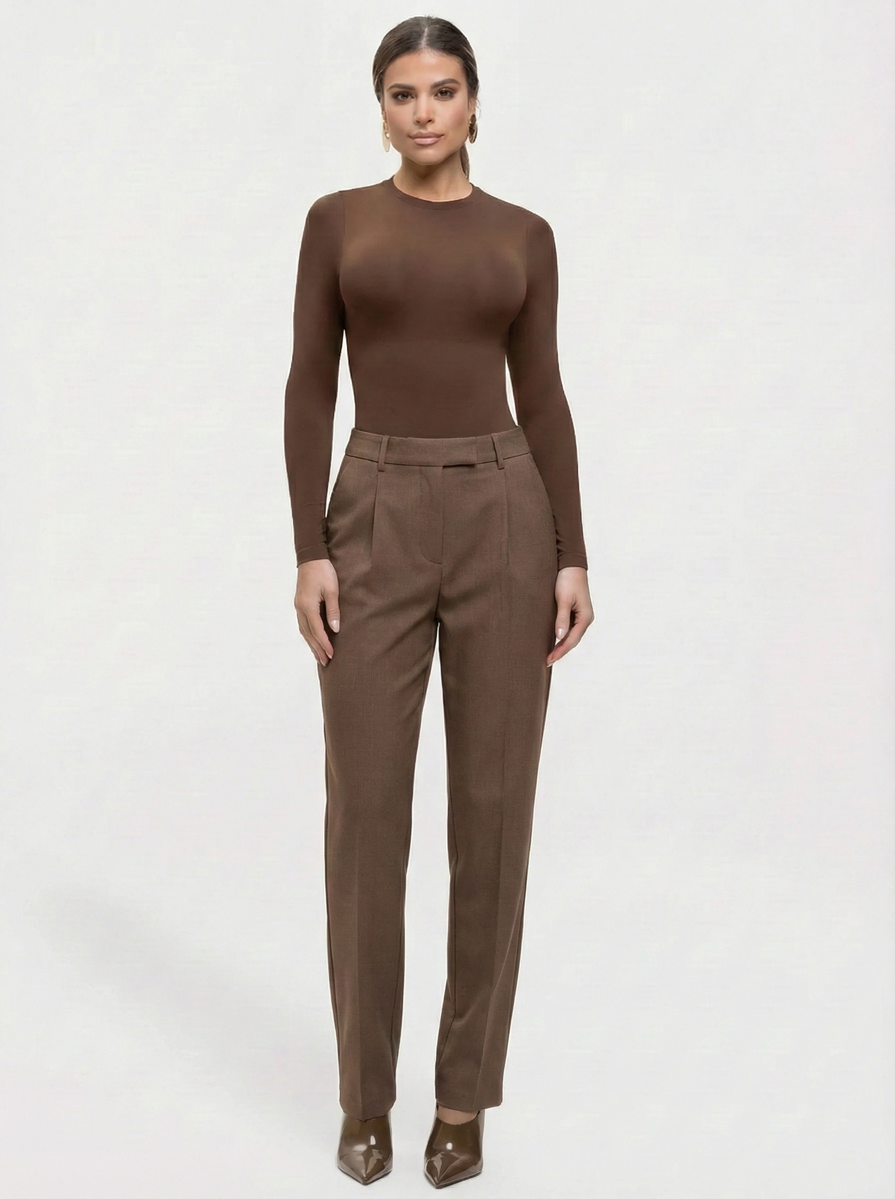 Woman wearing a brown long-sleeve top and pants on a white background