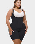 Woman wearing a black waist trainer over a white bralette on a plain background